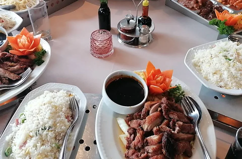 Een rijsttafel op de réchauds, met gesneden wortelbloemen op de schalen